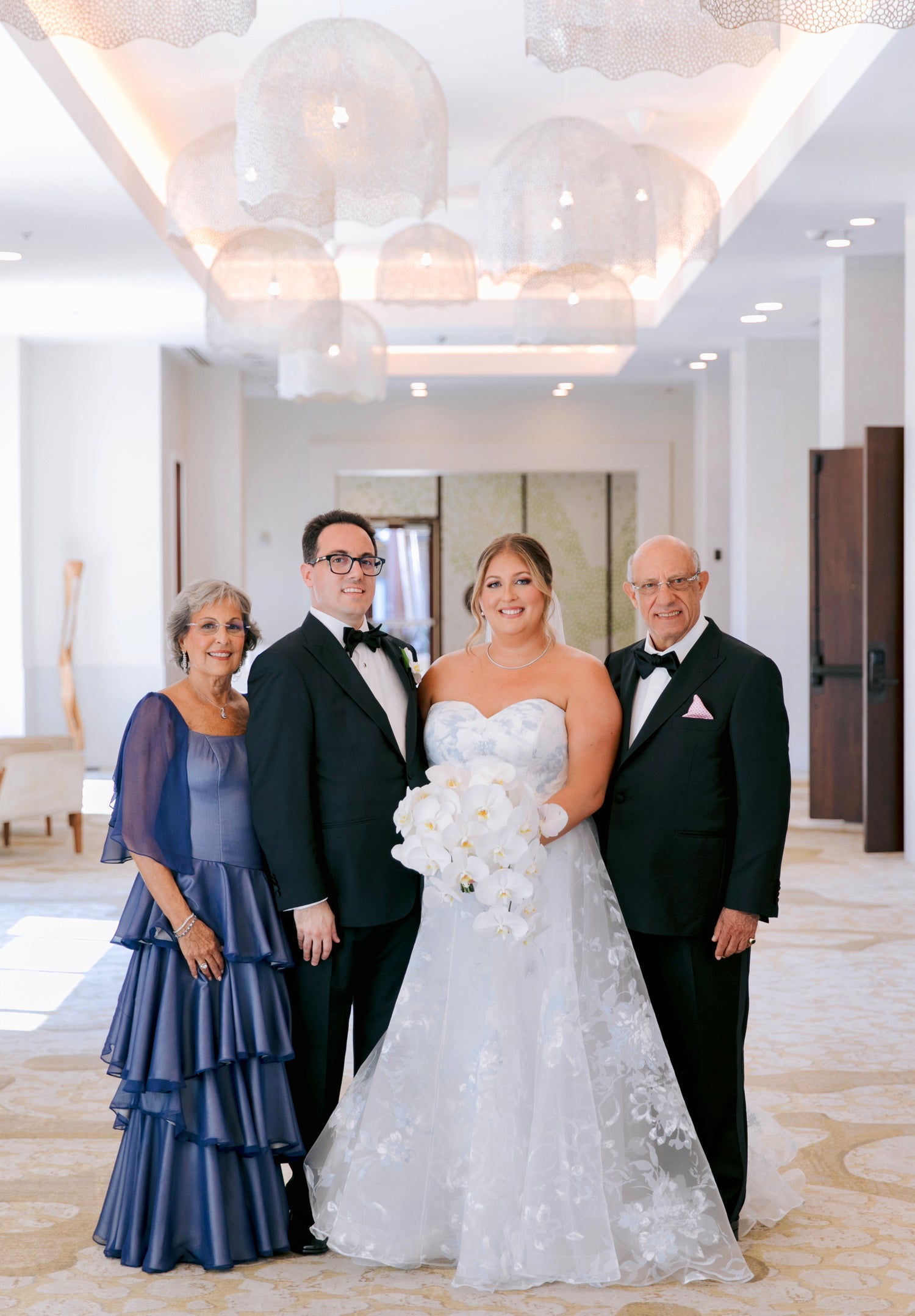 A bride in a white lace wedding gown, design by Alexas