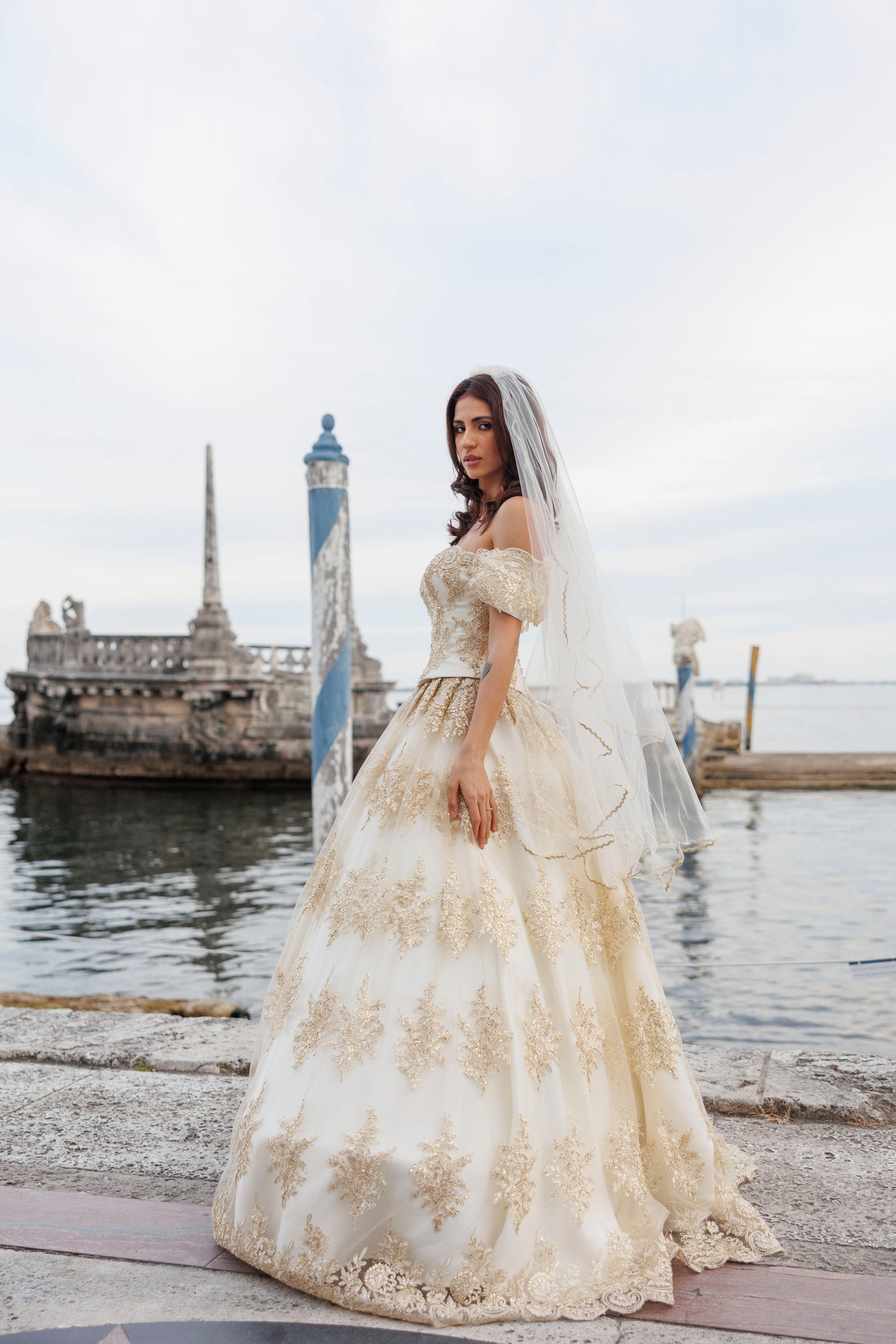 Woman in a white wedding dress with gold embroidery, design by Alexas
