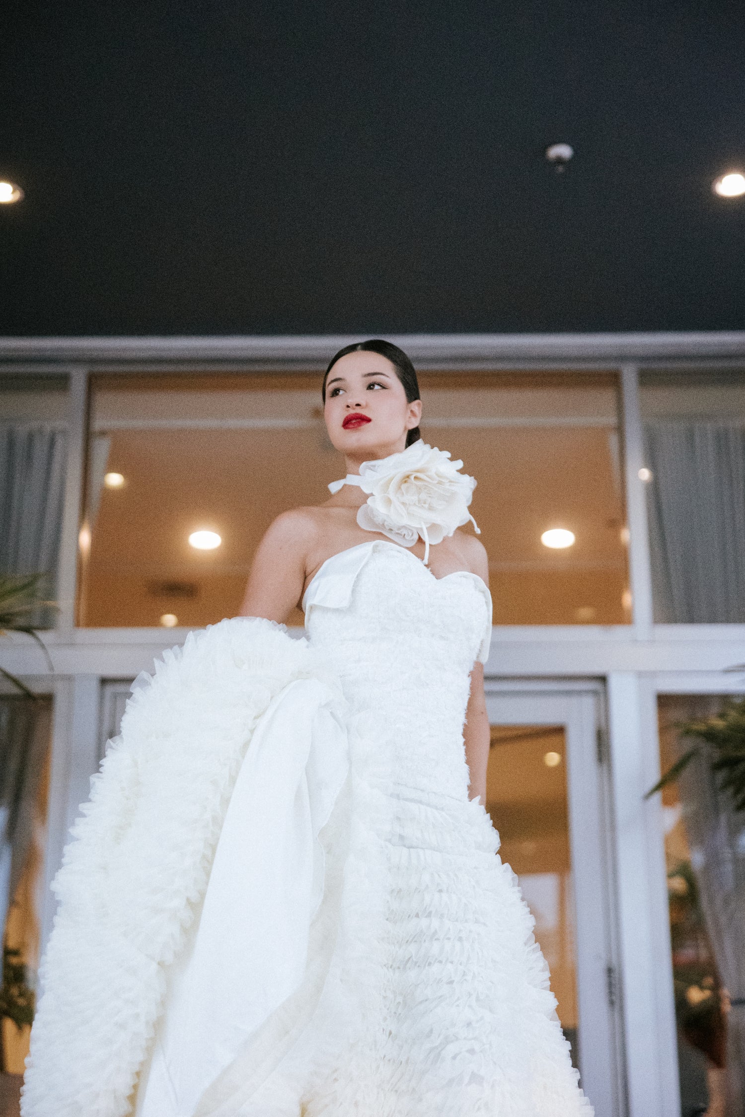 Woman in a white wedding dress with a floral detail, design by Alexas